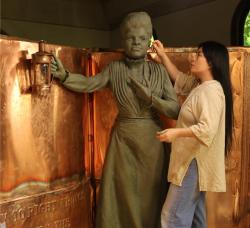 image of the artist at work on a sculpture in clay