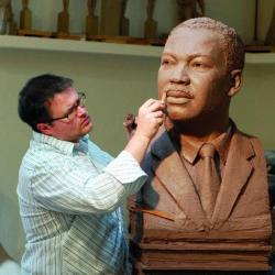 image of the artist at work on a sculpture in clay