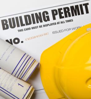 Image of building permit with hard hat and architectural plans.