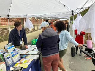 Sustainability and Resiliency staff talking to people at a table during fiesta en la calle